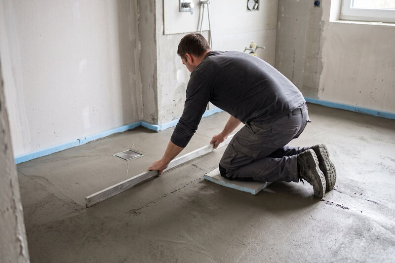 Handwerker zieht Gefälleestrich für eine bodengleiche Dusche ab